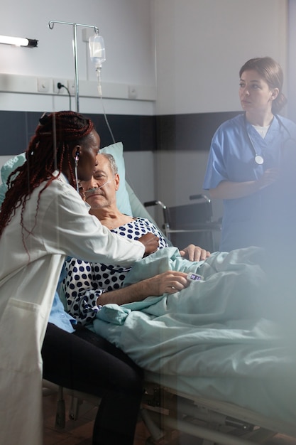 Photo cardiologue en uniforme examinant un homme âgé lors d'une visite médicale