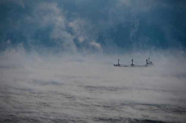 Un cargo passe par la mer dans le brouillard