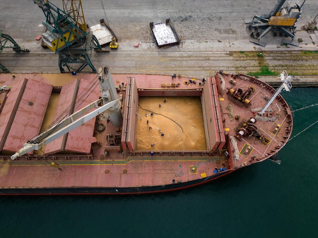 un cargo ou un vraquier chargé à ras bord de céréales se prépare au départ, les marins qui travaillent sur le pont terminent leur travail, vue aérienne de dessus