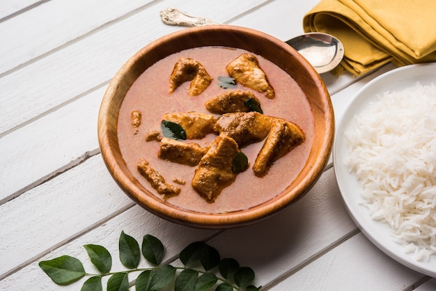 Cari de poisson savoureux servi avec du riz basmati cuit blanc avec des feuilles de curry en arrière-plan, nourriture indienne côtière préférée