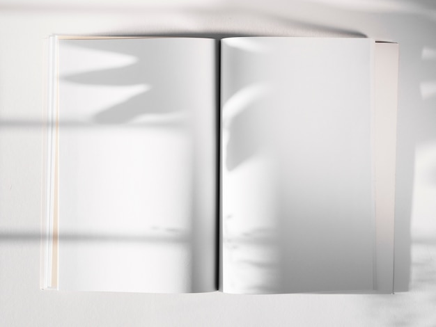 Photo carnet de croquis blanc sur fond blanc avec une ombre de feuille