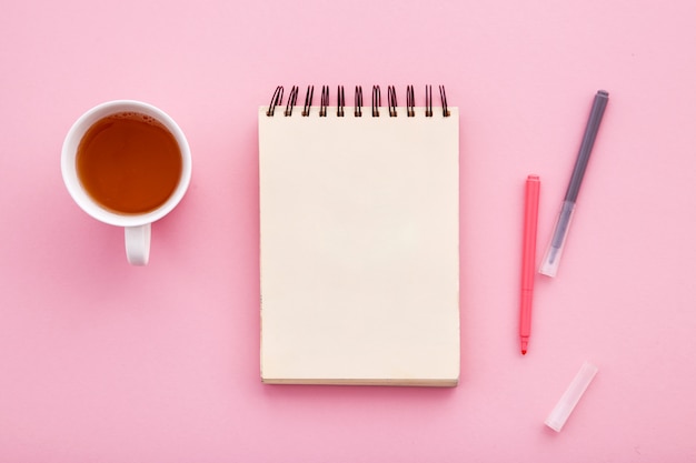 Carnet de croquis pour dessiner sur un fond coloré avec une tasse de thé.