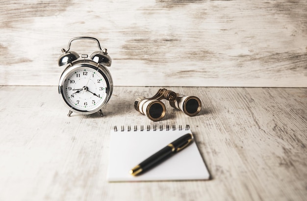 Carnet de jumelles et horloge sur la table