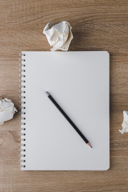 Photo carnet de notes avec des boules de papier froissées des feuilles vides sur une table en bois