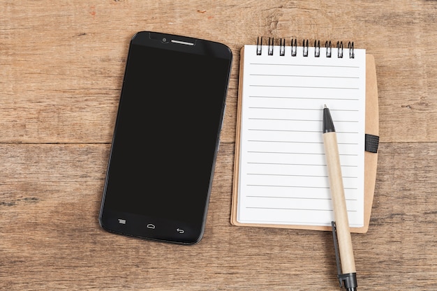 Carnet de notes et téléphone intelligent sur la table en bois.