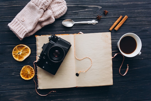 Carnet de souvenirs avec caméra et café sur table vintage en bois.