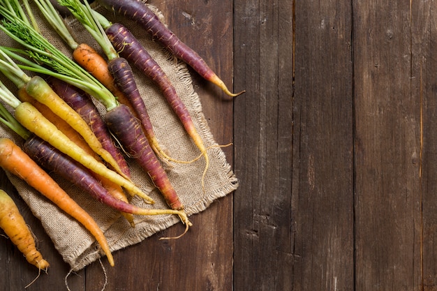 Carottes arc-en-ciel bio fraîches sur une vue de dessus de table en bois