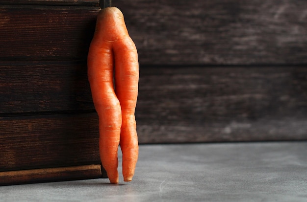 Carottes créatives fraîches sous forme de jambes sur un fond en bois