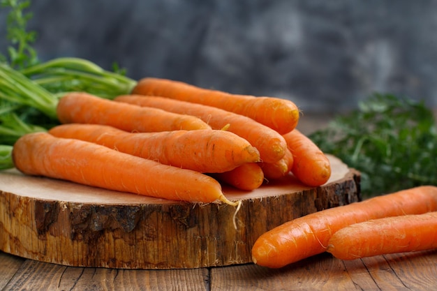 Carottes crues fraîches avec des feuilles sur une table en bois