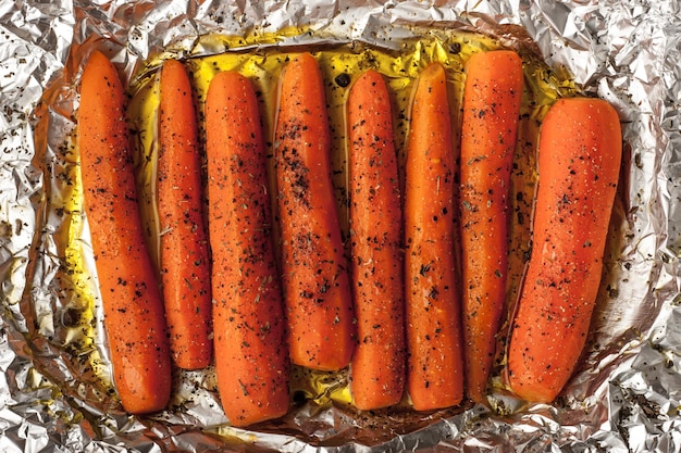 Carottes cuites au four avec du poivre noir sur une feuille de papier d'aluminium vue de dessus