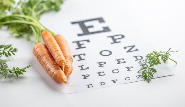 Carottes fraîches comme source de vitamine A placées sur le tableau d'examen oculaire