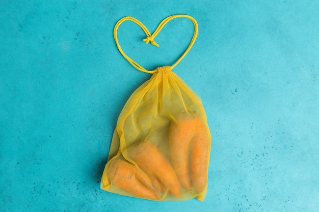 carottes laides à la mode en sac en filet réutilisable écologique jaune concept créatif shopping zéro déchet.