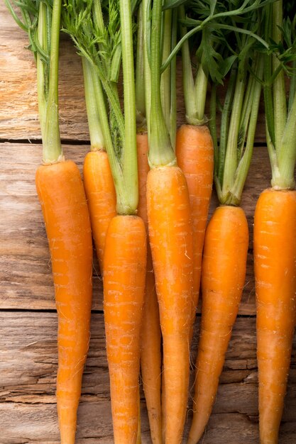 Carottes plus sur un fond en bois. Photographie de studio.