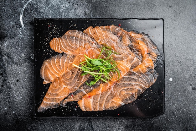 Carpaccio de saumon avec des microgreens sur planche de marbre Fond noir Vue supérieure