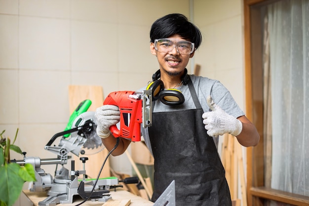 Carpenter holding electric jigsaw sur son atelier