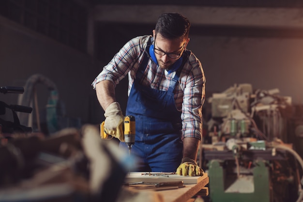 Carpenter perce un trou avec une perceuse électrique