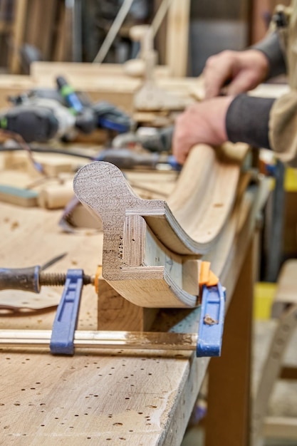 Carpenter sands flexion balustrade en bois avec du papier de verre en gros plan de l'atelier