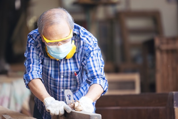 Carpenter, Senior man ponçage d'une clôture en bois sur le lieu de travail à l'aide de l'outil de travail