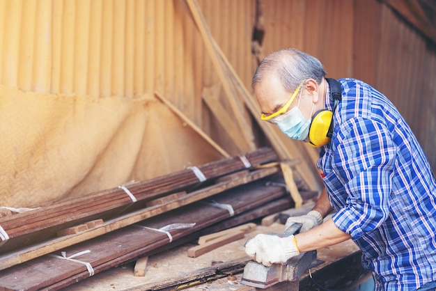 Carpenter, Senior man ponçage d'une clôture en bois sur le lieu de travail à l'aide de l'outil de travail