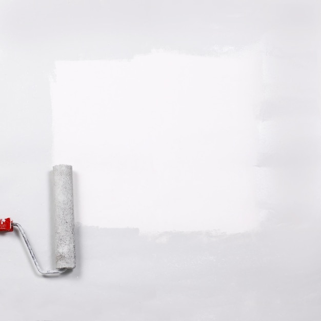 Carré peint en blanc avec le rouleau à peinture sur une feuille blanche de