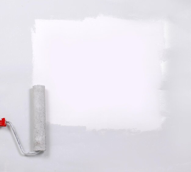 Photo carré peint en blanc avec le rouleau à peinture sur une feuille blanche de