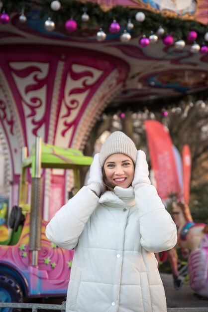 Carrousel d'attractions juste fille vêtue d'une veste blanche et d'un chapeau blanc la fille sourit fille se réjouit des émotions Célébrer Noël en plein air