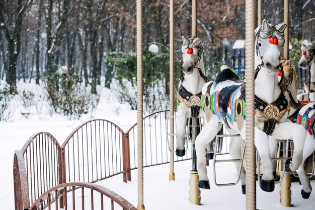 Photo carrousel à chevaux dans le parc d'hiver paysage de neige d'hivers avec rond-point de carrousel rétro