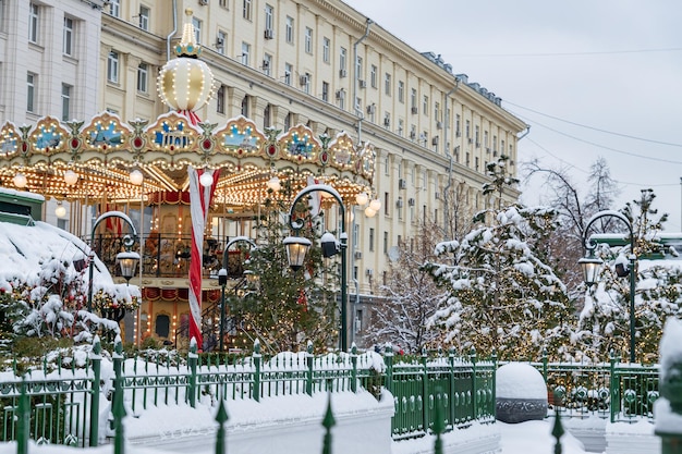 Carrousel festif de Merrygoround sur la place d'hiver à Moscou parmi les arbres de Noël Paysage urbain enneigé magique