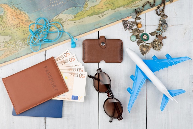 Carte d'avion passeport argent portefeuille lunettes de soleil sur table en bois blanc