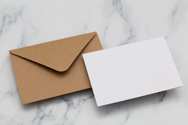 Carte blanche vierge avec enveloppe en papier kraft brun sur fond de marbre
