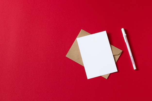 Photo carte blanche vierge avec un stylo. feuille de papier blanc vide isolé sur fond rouge