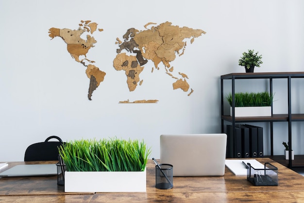Une carte en bois est accrochée à un mur clair du bureau Une carte du monde dans un intérieur élégant
