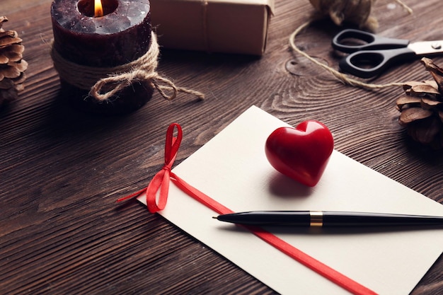 Carte-cadeau pour la Saint-Valentin avec stylo et bougie sur fond de bois