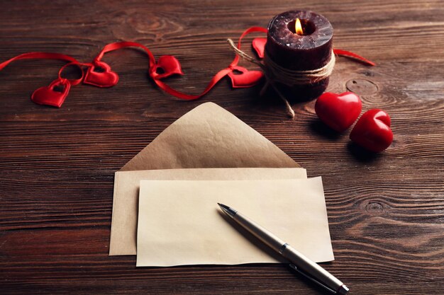 Photo carte-cadeau pour la saint-valentin avec stylo et bougie sur fond de bois