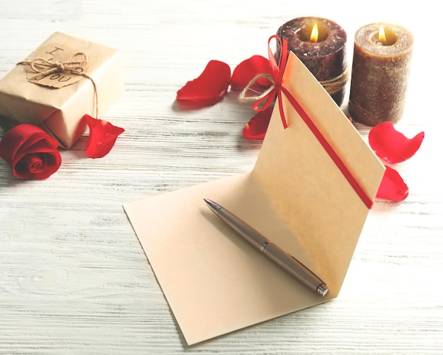 Carte-cadeau pour la Saint-Valentin avec stylo fort et bougies sur fond de bois blanc