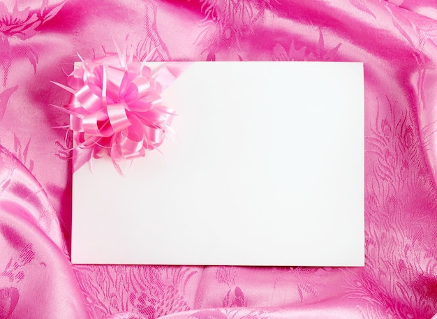 Photo carte-cadeau vide avec ruban sur satin rose