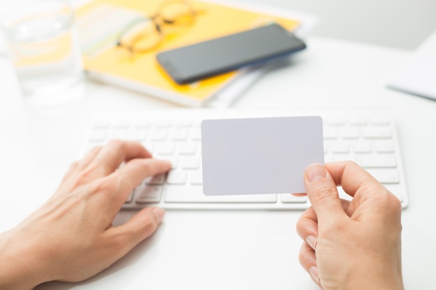 Carte de crédit blanche vierge en main sur le clavier.