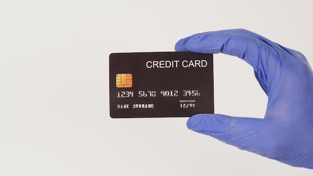 Une carte de crédit noire à la main et porter des gants en latex violet ou violet isolés sur fond blanc