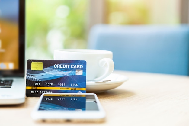 Carte de crédit d'un ordinateur portable, smartphone et tasse à café sur une table en bois