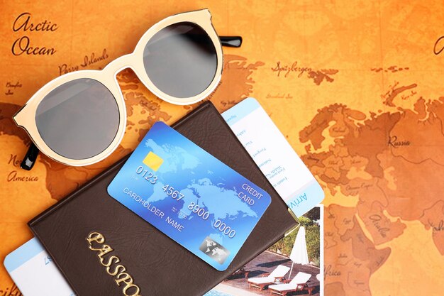Photo carte de crédit avec passeport et billet pour des vacances sur fond de carte du monde