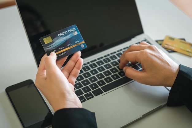 Carte de crédit pour payer, femme tenant au paiement et faisant des achats en ligne avec un ordinateur portable, substitut pour l'utilisation d'espèces. paiement par prélèvement électronique.