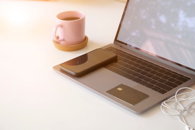 Carte de crédit et smartphone sur ordinateur portable et tasse à café avec table de bureau.