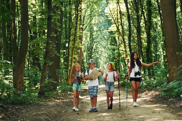 Avec carte Enfants se promenant en forêt avec matériel de voyage