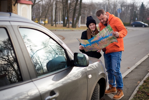 Carte entre les mains des jeunes sur la route avec une voiture.