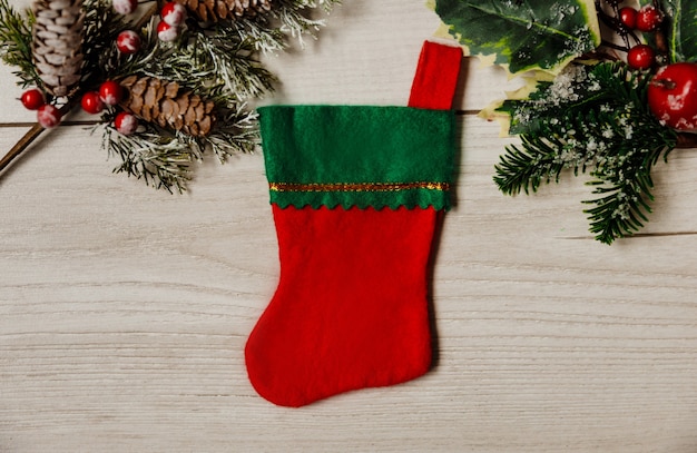 Carte festive de noël et du nouvel an avec une chaussette rouge et verte sur fond de bois gris