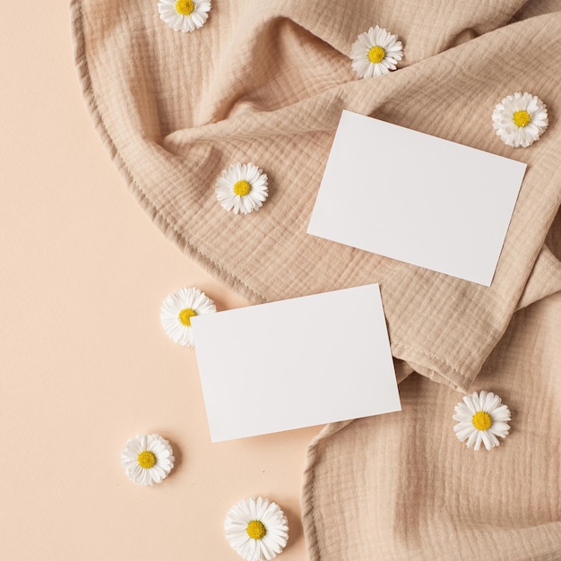 Carte de feuille de papier vierge avec espace de copie de maquette bourgeons de fleurs de camomille et tissu de mousseline sur fond beige neutre Modèle de marque d'entreprise esthétique minimal Vue de dessus à plat