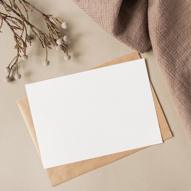 Photo carte de feuille de papier vierge avec espace de copie de maquette et branche florale sèche et tissu de couverture sur fond beige neutre modèle d'invitation de mariage esthétique minimal vue de dessus à plat