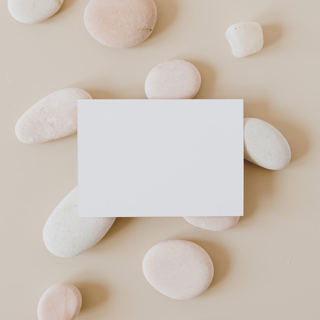 Carte de feuille de papier vierge avec des pierres sur beige