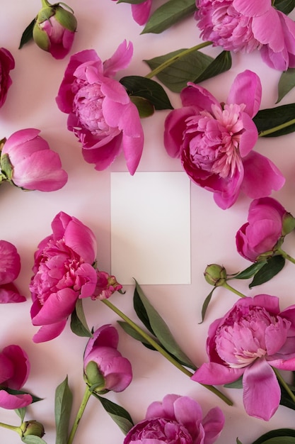 Carte d'invitation en papier vierge avec espace de copie Bouquet de fleurs de pivoine rose sur fond rose élégant pastel neutre Vue de dessus à plat Composition florale minimale