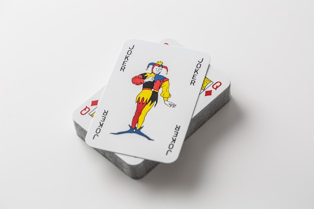 Carte Joker au-dessus d'une pile de cartes à jouer sur un fond blanc isolé.